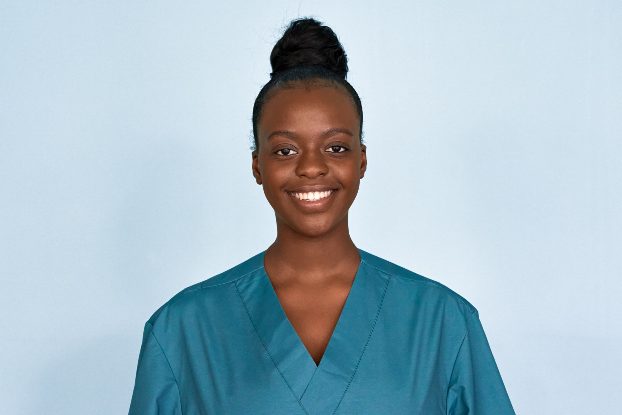 Happy young female african american scrub nurse wear blue uniform standing isolated on background. Black millennial woman medical student, intern, medic staff professional head shot close up portrait.