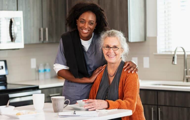 A woman and an older woman are seated together at a kitchen table, engaged in conversation.