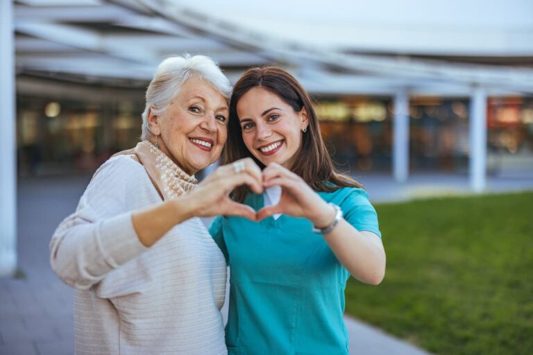 A woman and an older woman create a heart shape with their hands, symbolizing love and connection between generations.